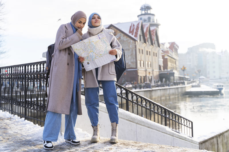 Dua muslimah mengenakan jilbab membaca peta saat traveling di kawasan kota Yogyakarta saat hari cerah.