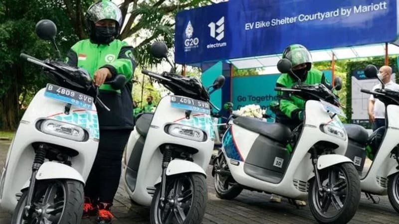 Seseorang sedang memegang stang motor listrik modern dengan panel instrumen digital